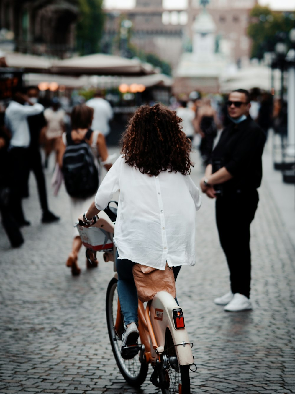 mulher na camisa branca da manga comprida que anda na bicicleta durante o dia