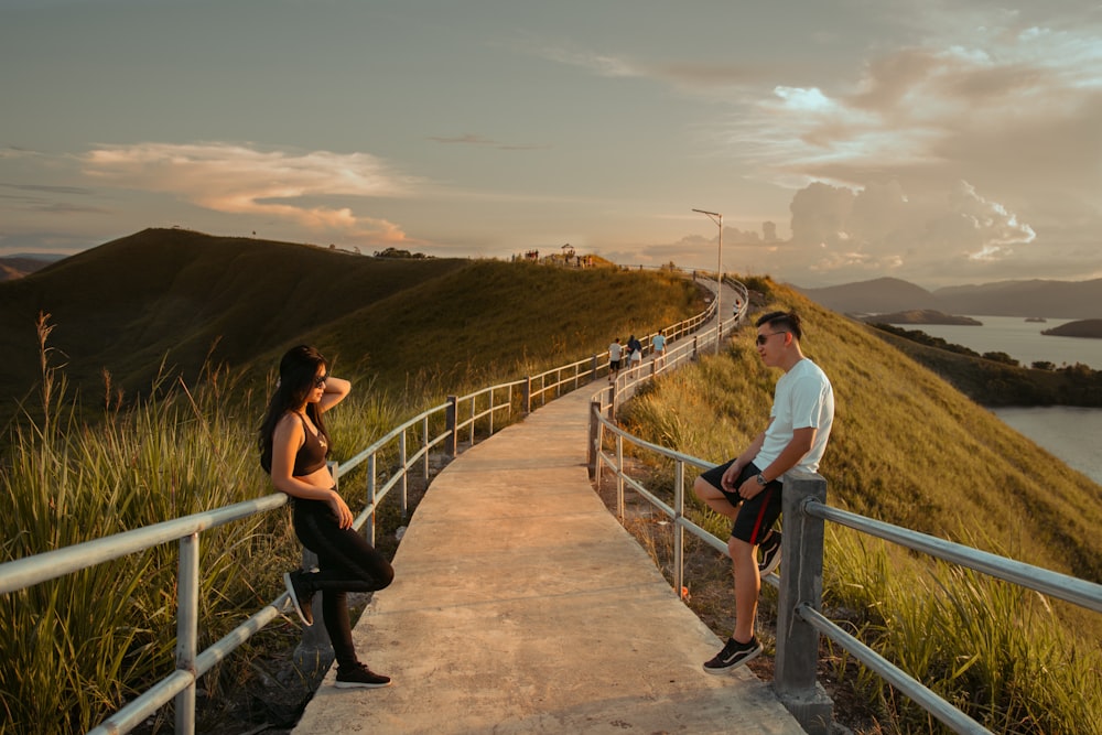 man and woman standing on brown wooden bridge during daytime