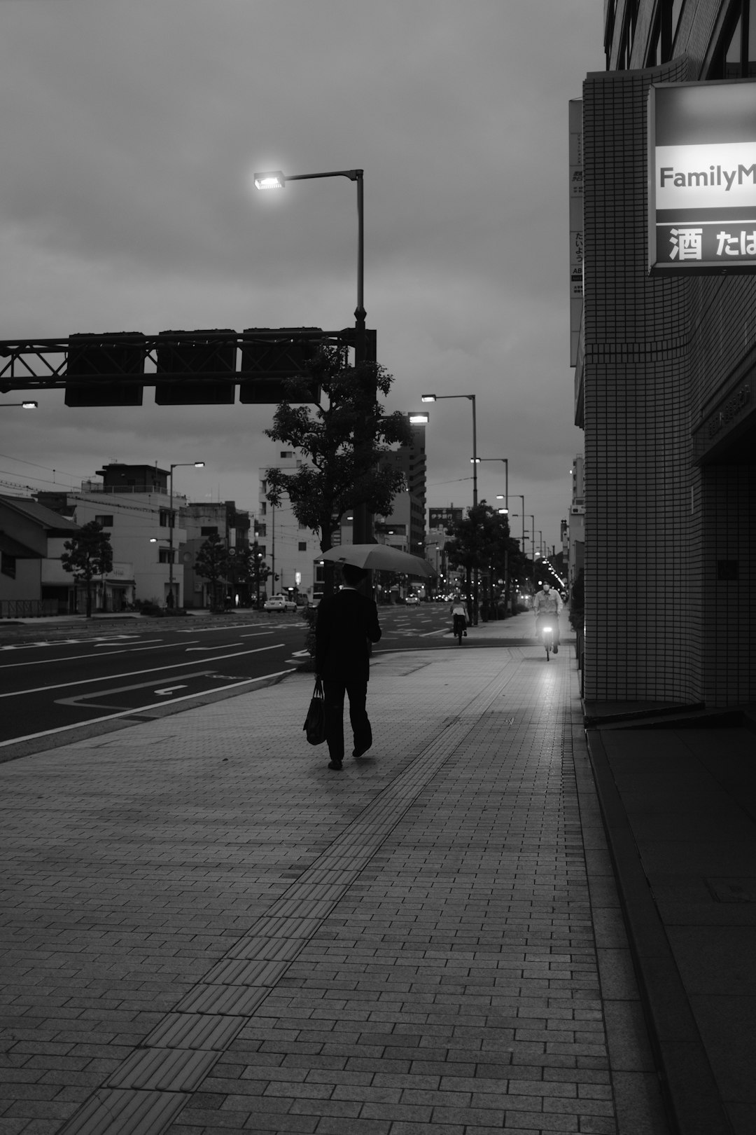 grayscale photo of man walking on sidewalk
