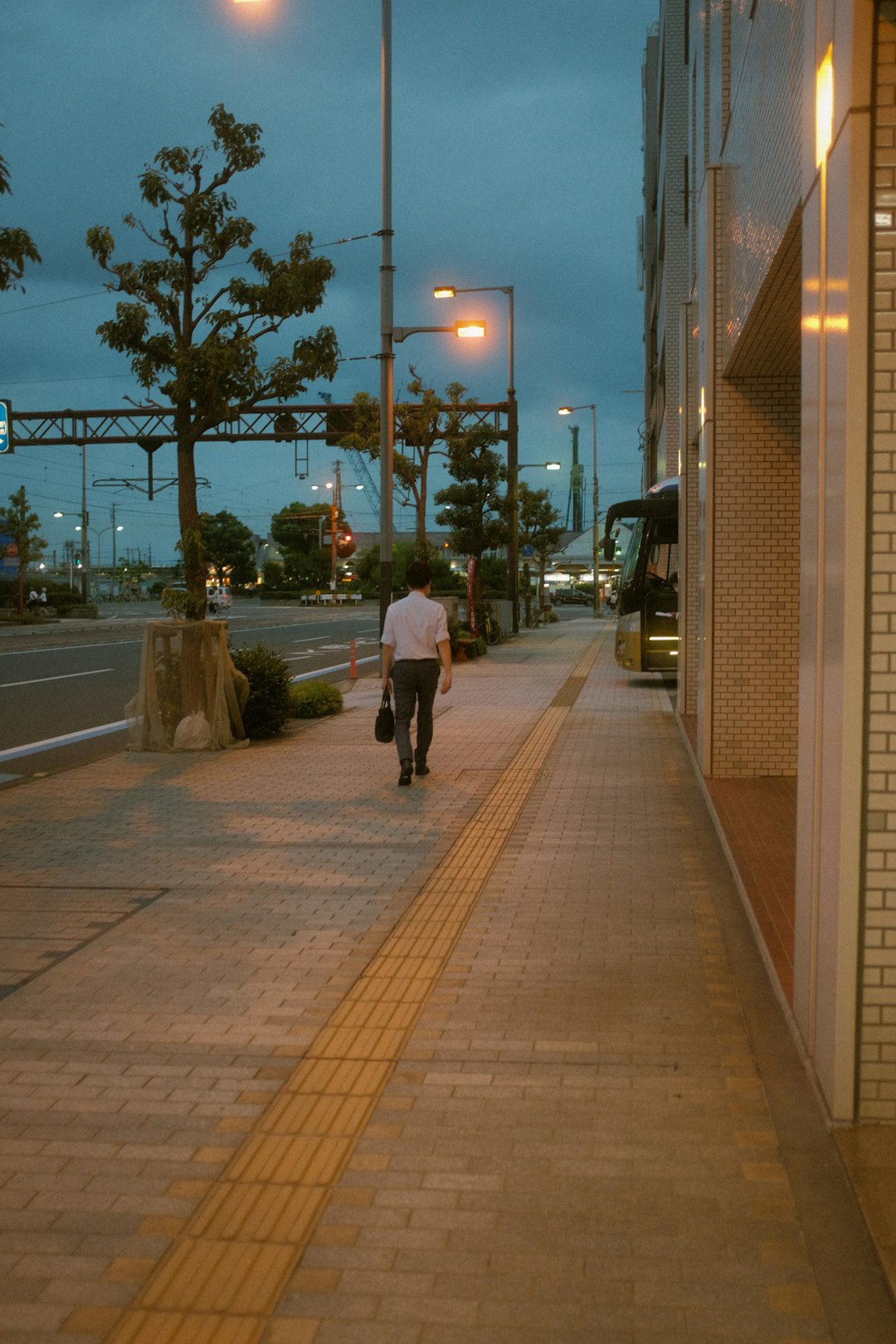 man in white long sleeve shirt and black pants walking on sidewalk during night time