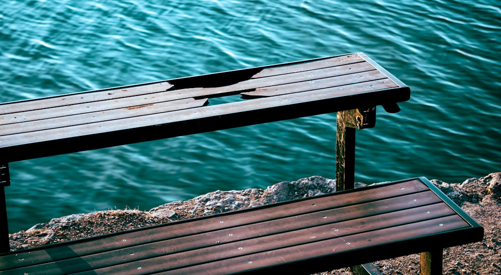 brown wooden bench near body of water during daytime