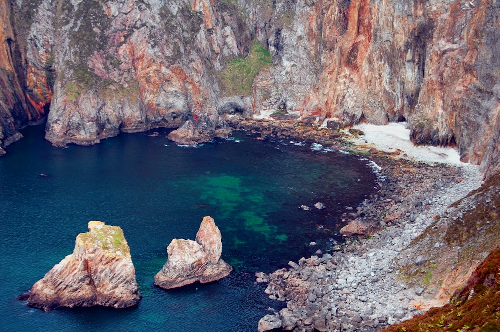 brown rocky mountain beside blue sea during daytime