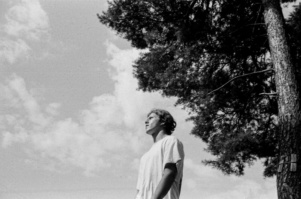 man in white t-shirt standing near tree