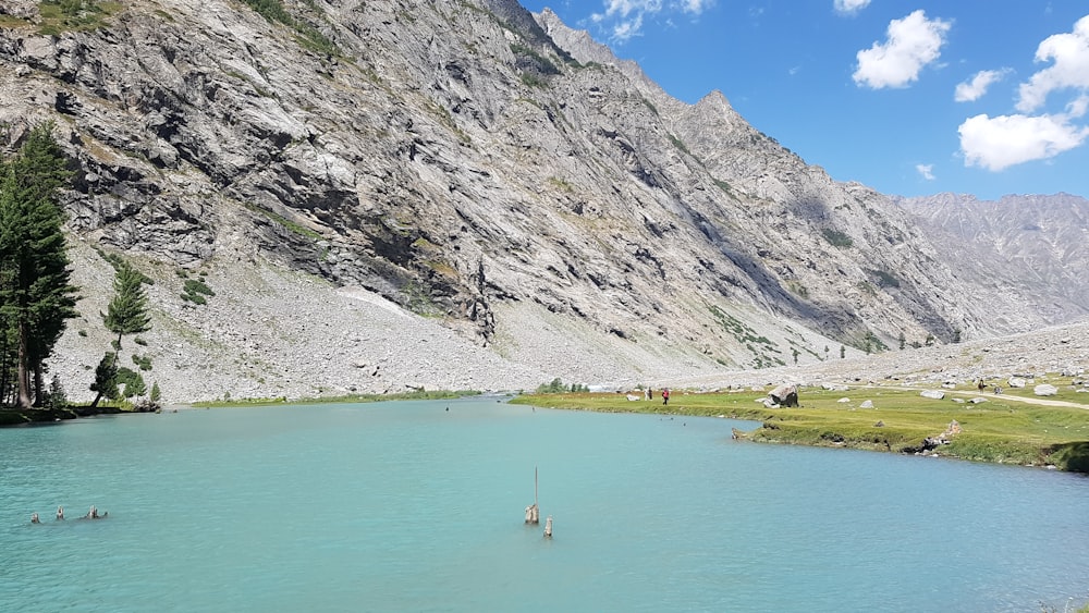 people on body of water near mountain during daytime