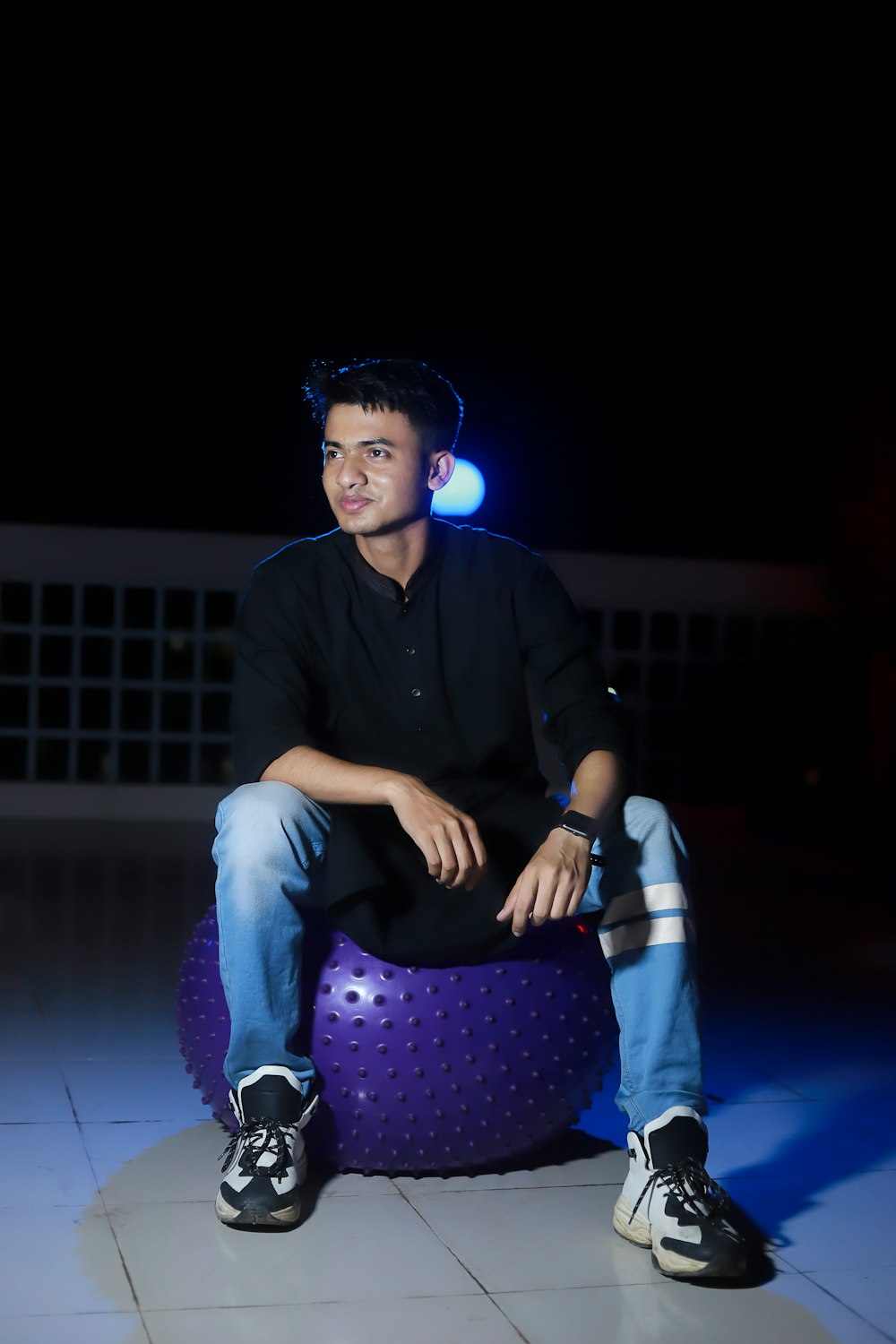 man in black dress shirt and purple pants sitting on blue floor