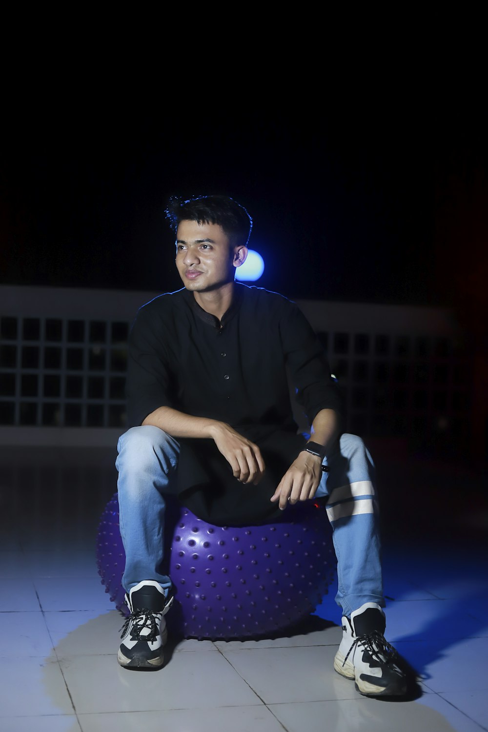 man in black dress shirt and purple pants sitting on blue floor