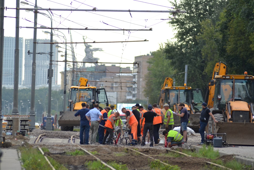 group of people standing near yellow heavy equipment during daytime