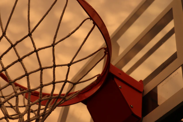 Close-up of a handmade basketball net hanging on an outdoor hoop, sunlight casting warm shadows.