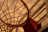Close-up of a handmade basketball net hanging on a weathered outdoor hoop in golden afternoon light.
