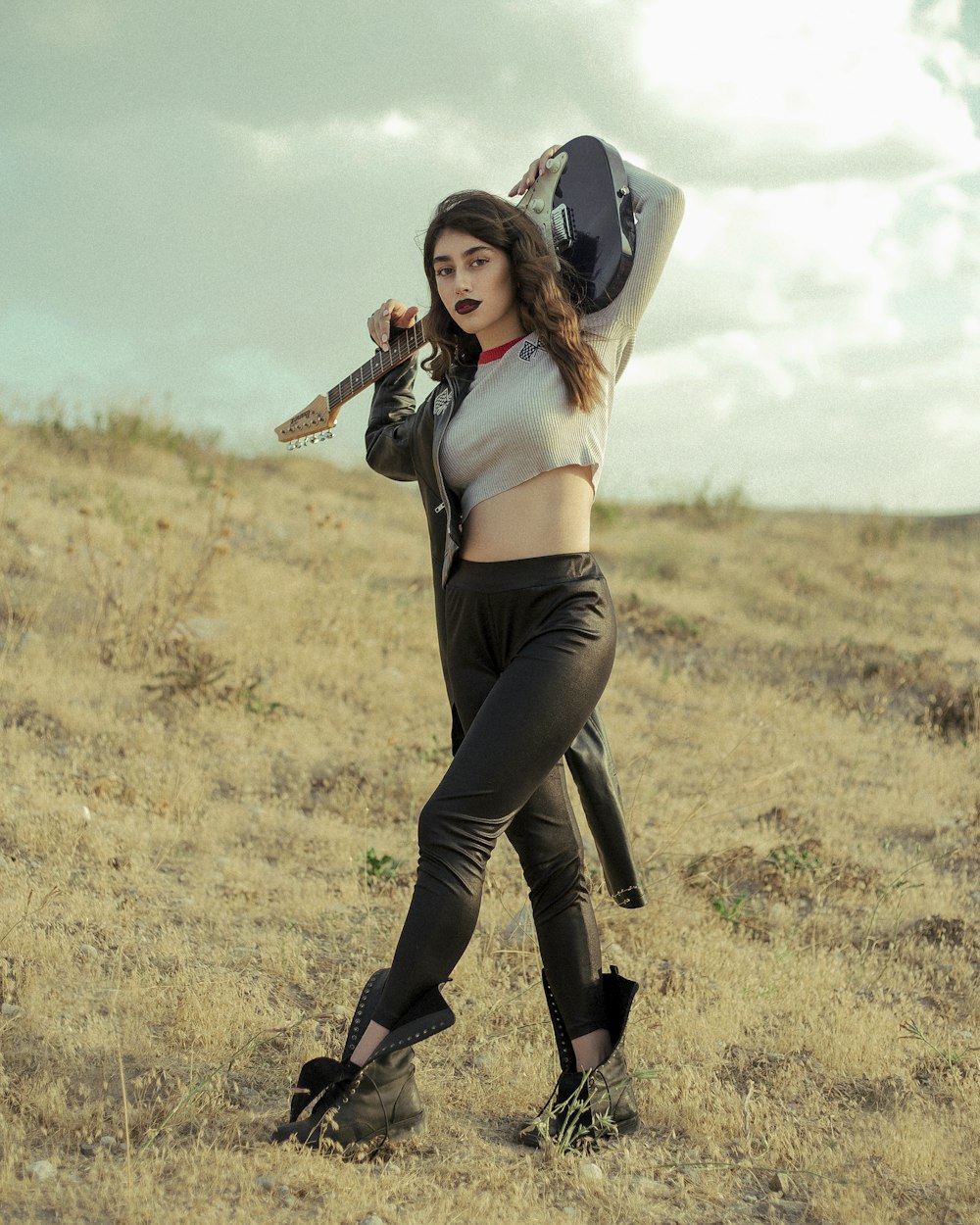 woman in black pants and white crop top holding brown acoustic guitar