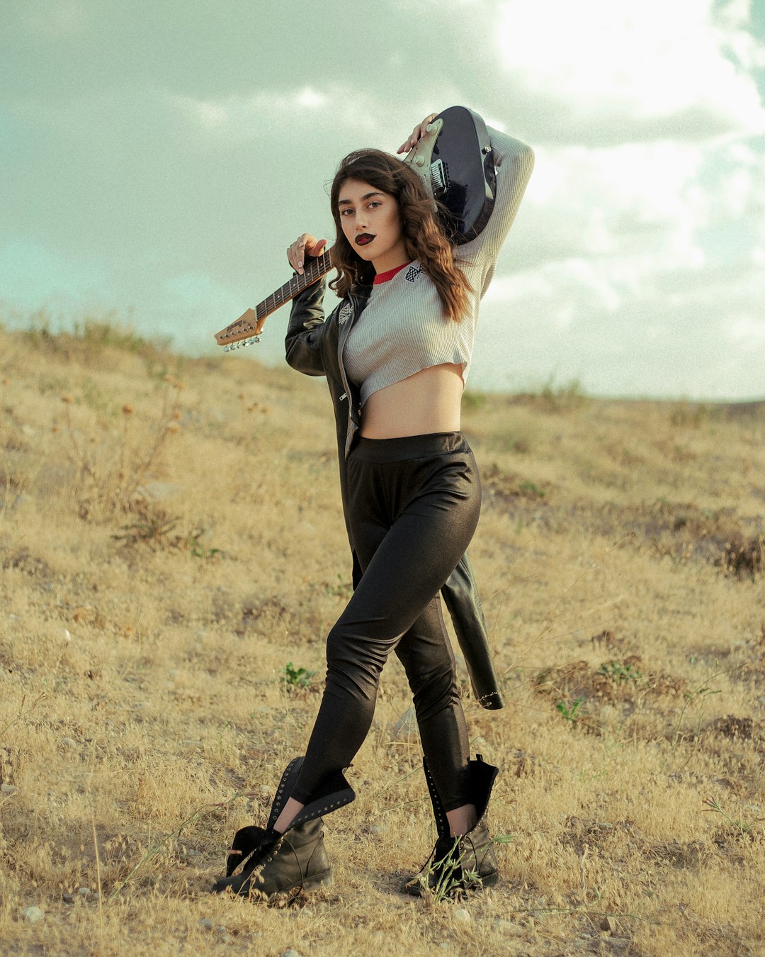 woman in black pants and white crop top holding brown acoustic guitar