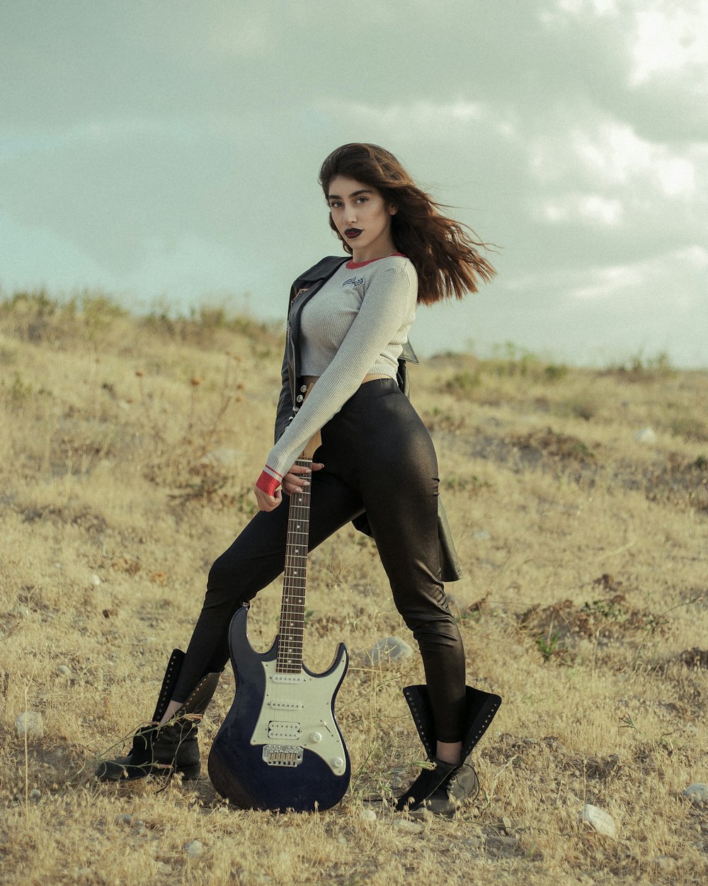 woman in gray long sleeve shirt playing black electric guitar