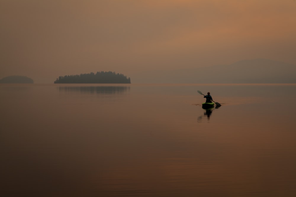 person in black jacket and pants riding on boat on calm water