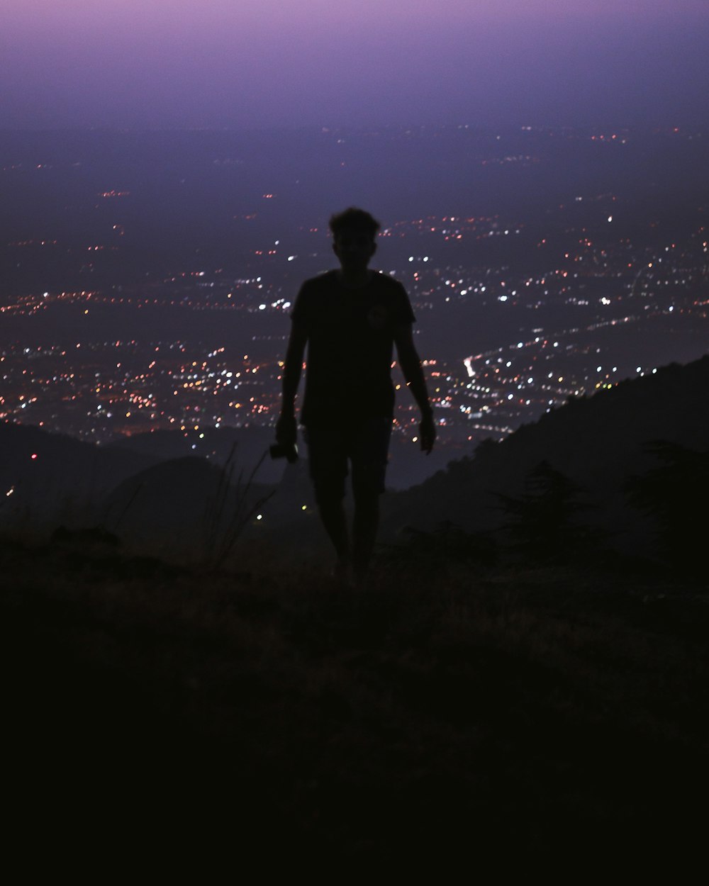 silhouette of man standing on hill during night time