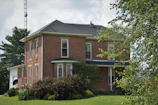Wide shot of a newly built brick house surrounded by greenery.