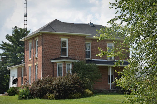Wide shot of a newly built brick house surrounded by greenery.
