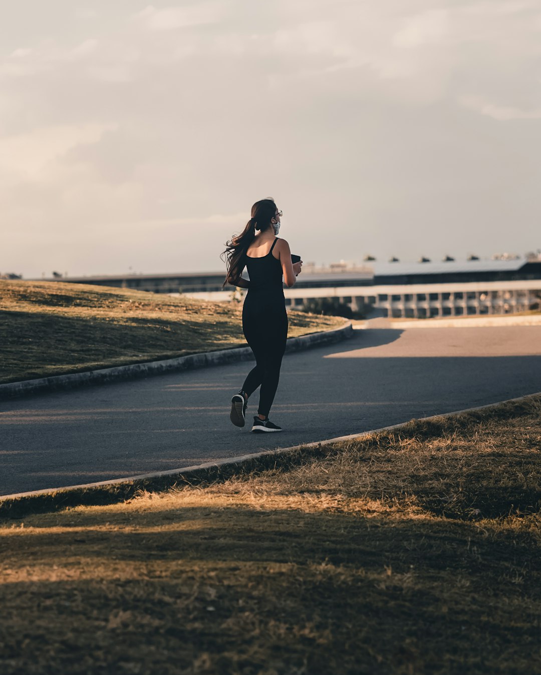 woman in black tank top and black pants standing on gray concrete pavement during daytime