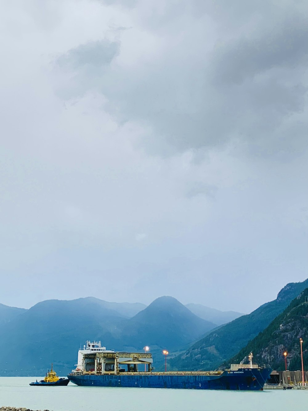 white and brown building near green mountains under white sky during daytime