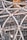 Detailed view of a complex steel structure with interconnected metal beams and support scaffolding. Numerous pipes and girders crisscross in a geometric pattern, accompanied by visible construction elements such as scaffolding and a yellow crane in the background. The scene captures an intricate industrial design, showcasing the framework of a developing building or structure.