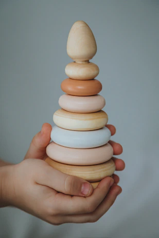 A set of wooden stacking rings in pastel colors on a soft fabric.