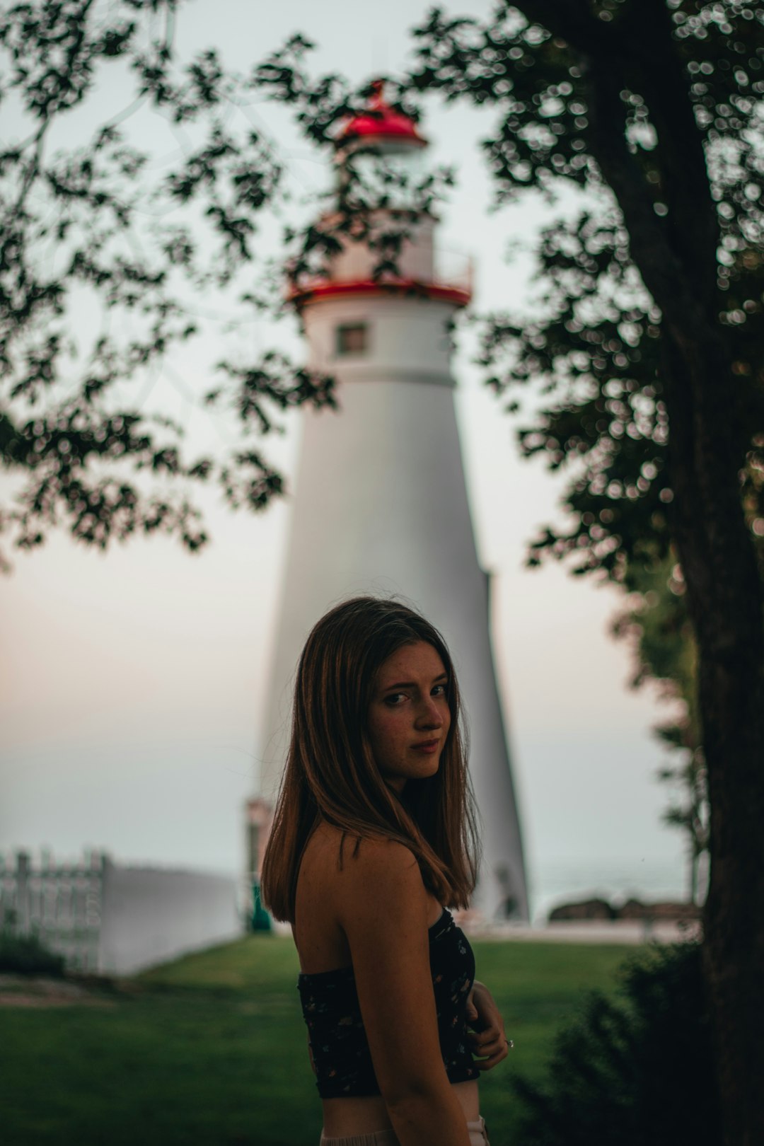 woman in black bikini top standing near white and red lighthouse during daytime