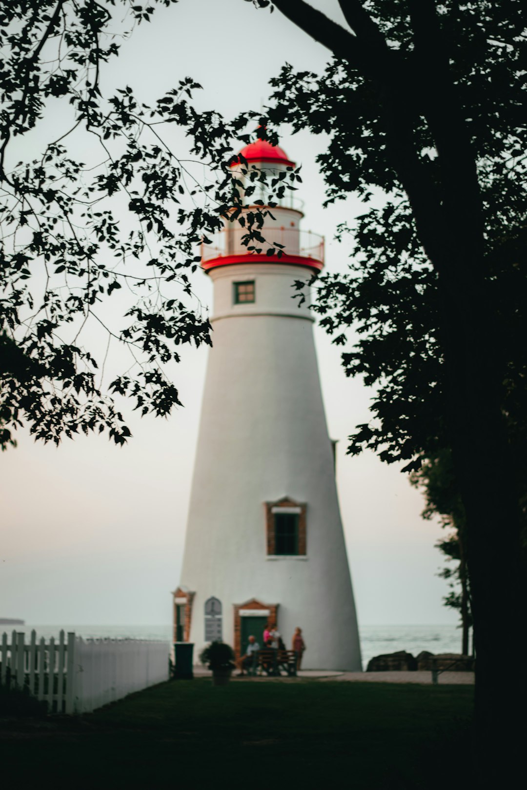 white concrete lighthouse near green trees during daytime