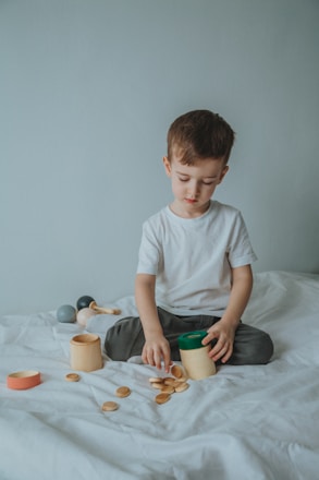 boy in white crew neck t-shirt sitting on bed