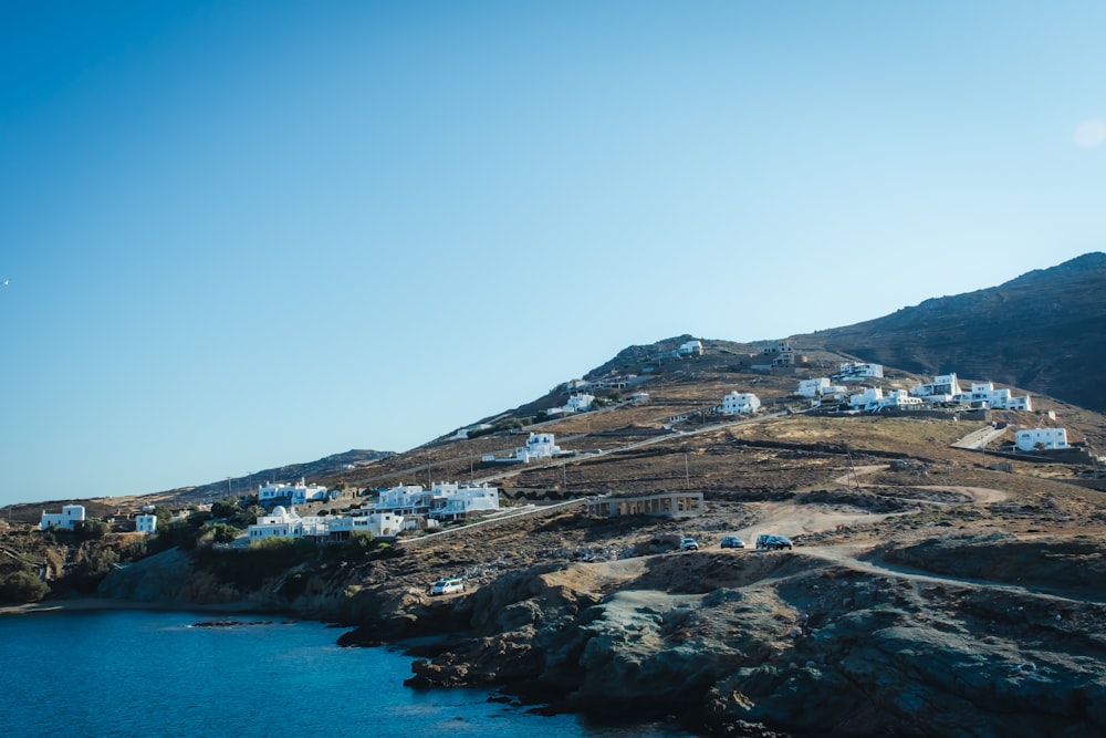 brown rocky mountain beside blue sea under blue sky during daytime