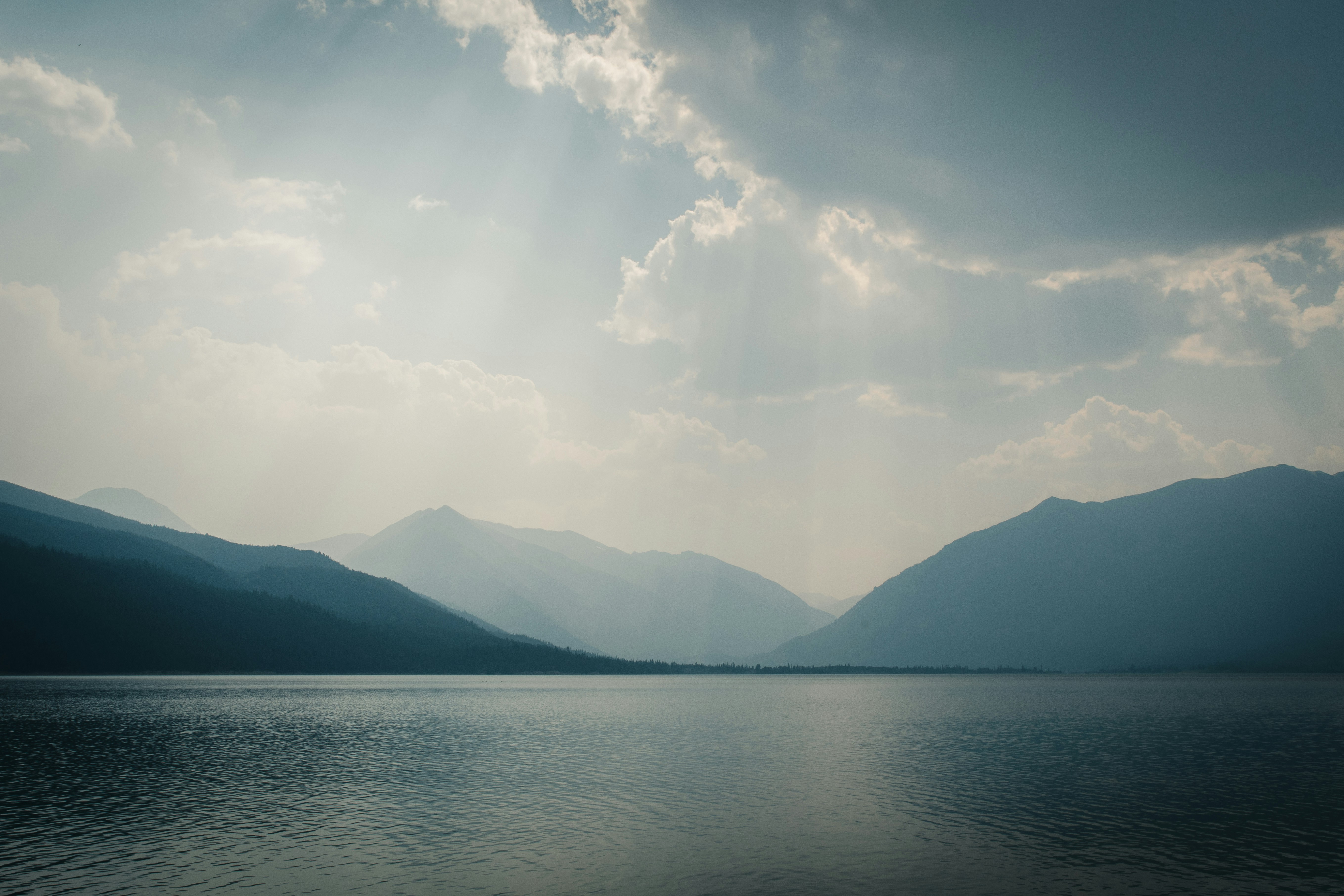 body of water near mountain under white clouds and blue sky during daytime, 