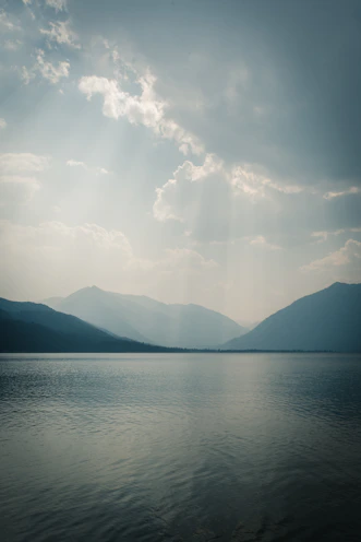 Soft sunlight filters through Erhai Lake's gentle waves with distant mountains under a warm sky.