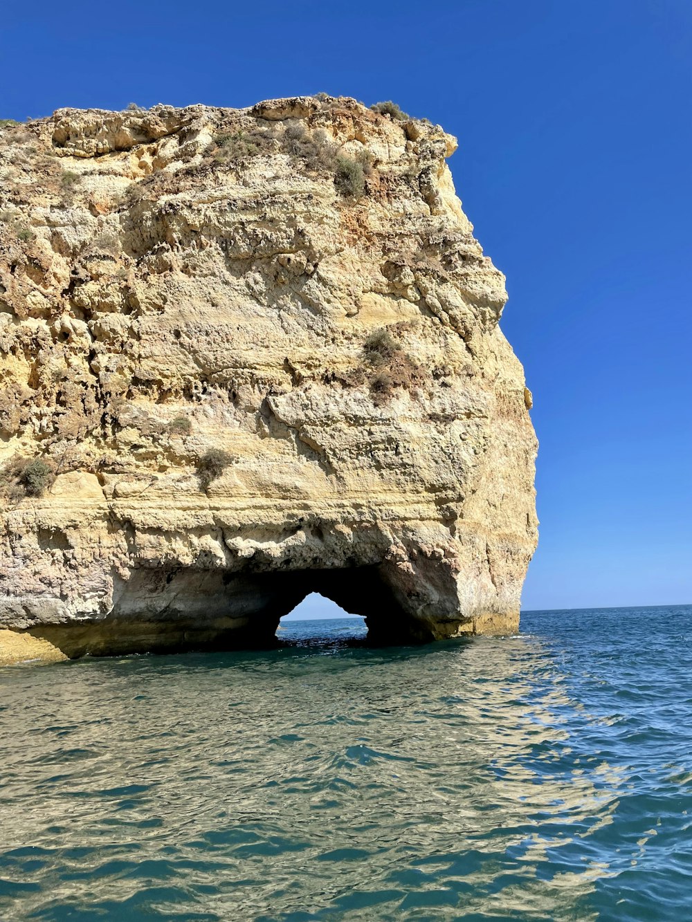 brown rock formation on sea under blue sky during daytime