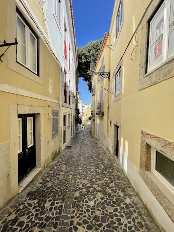 An ancient cobblestone alleyway lined with charming old buildings and flowering balconies.