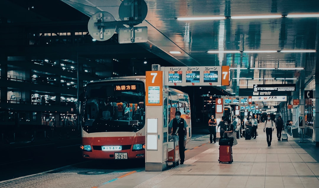 people walking on sidewalk near red bus during night time