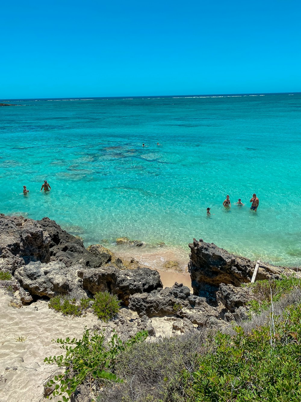 people swimming on beach during daytime