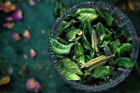 A close-up image of green moringa leaves powder, catappa leaves, and handmade bamboo crafts artfully arranged on a wooden table.