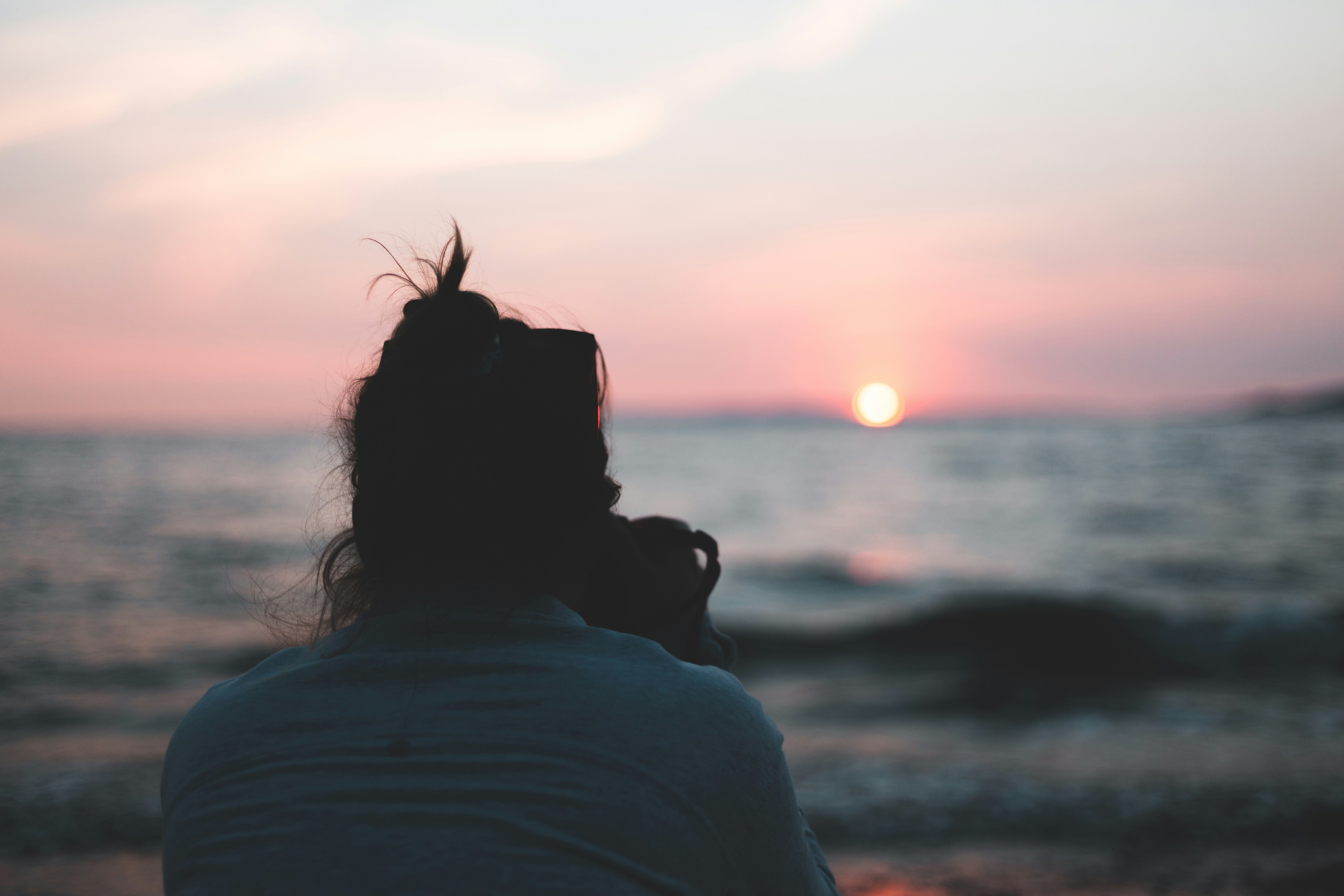 woman in white shirt standing near sea during sunset