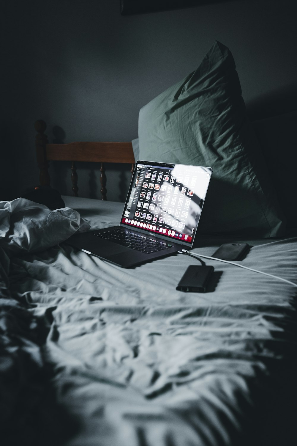 macbook pro on bed near black smartphone
