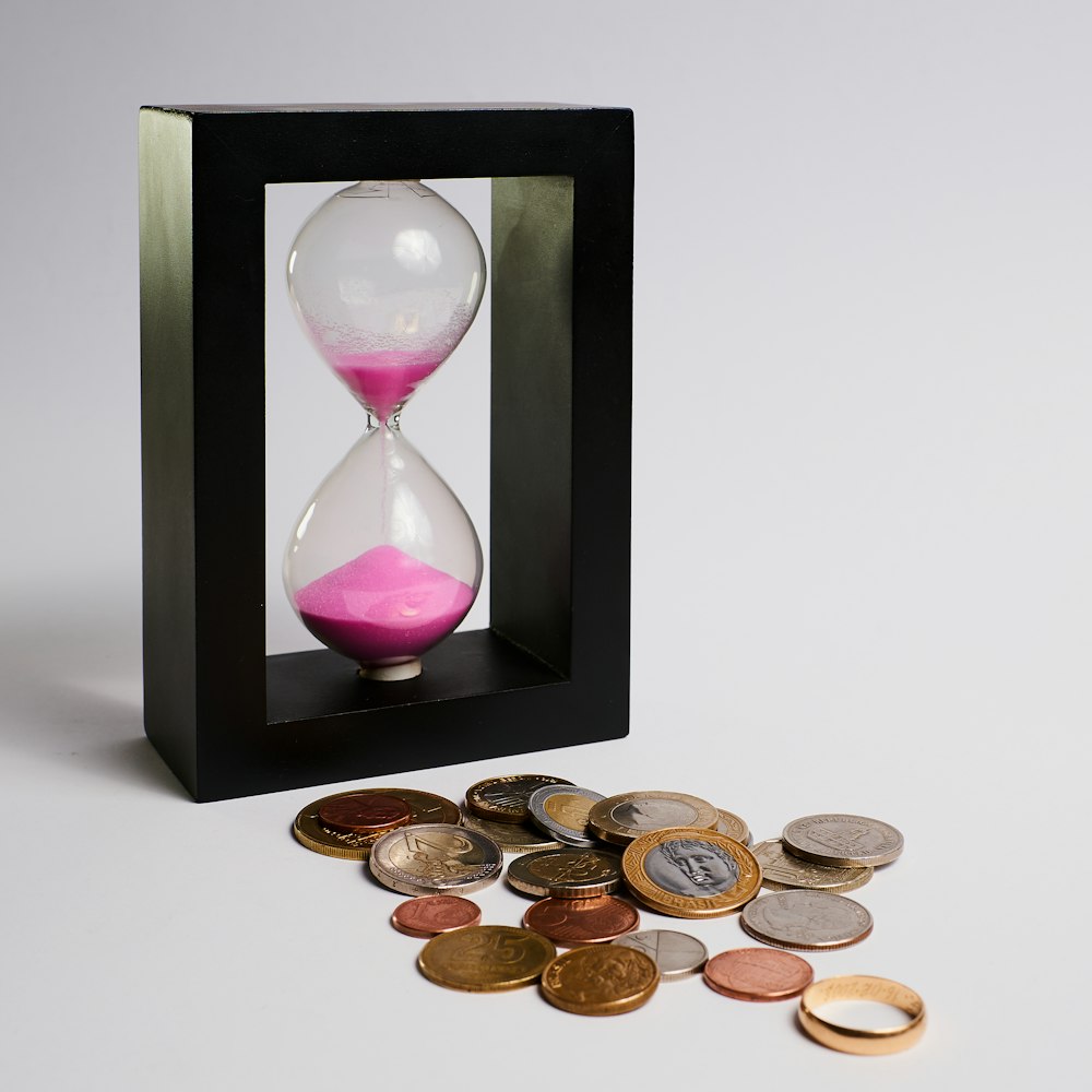 A sand timer is placed next to some coins.