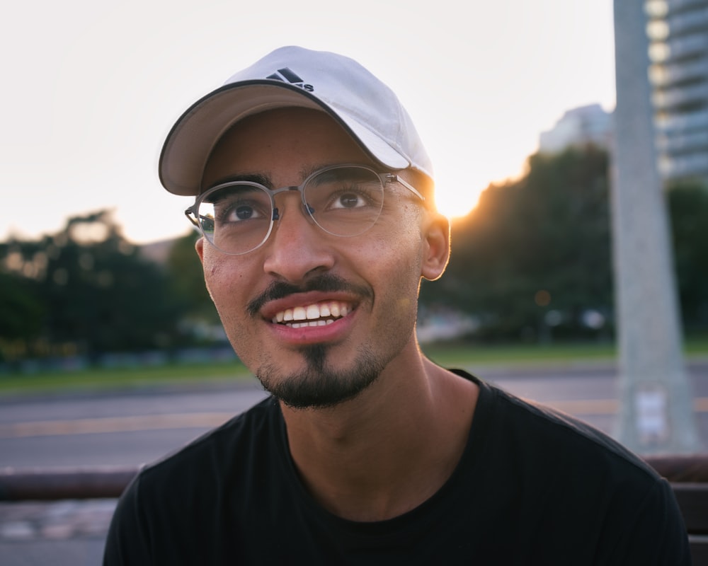 man in black crew neck shirt wearing white cap smiling