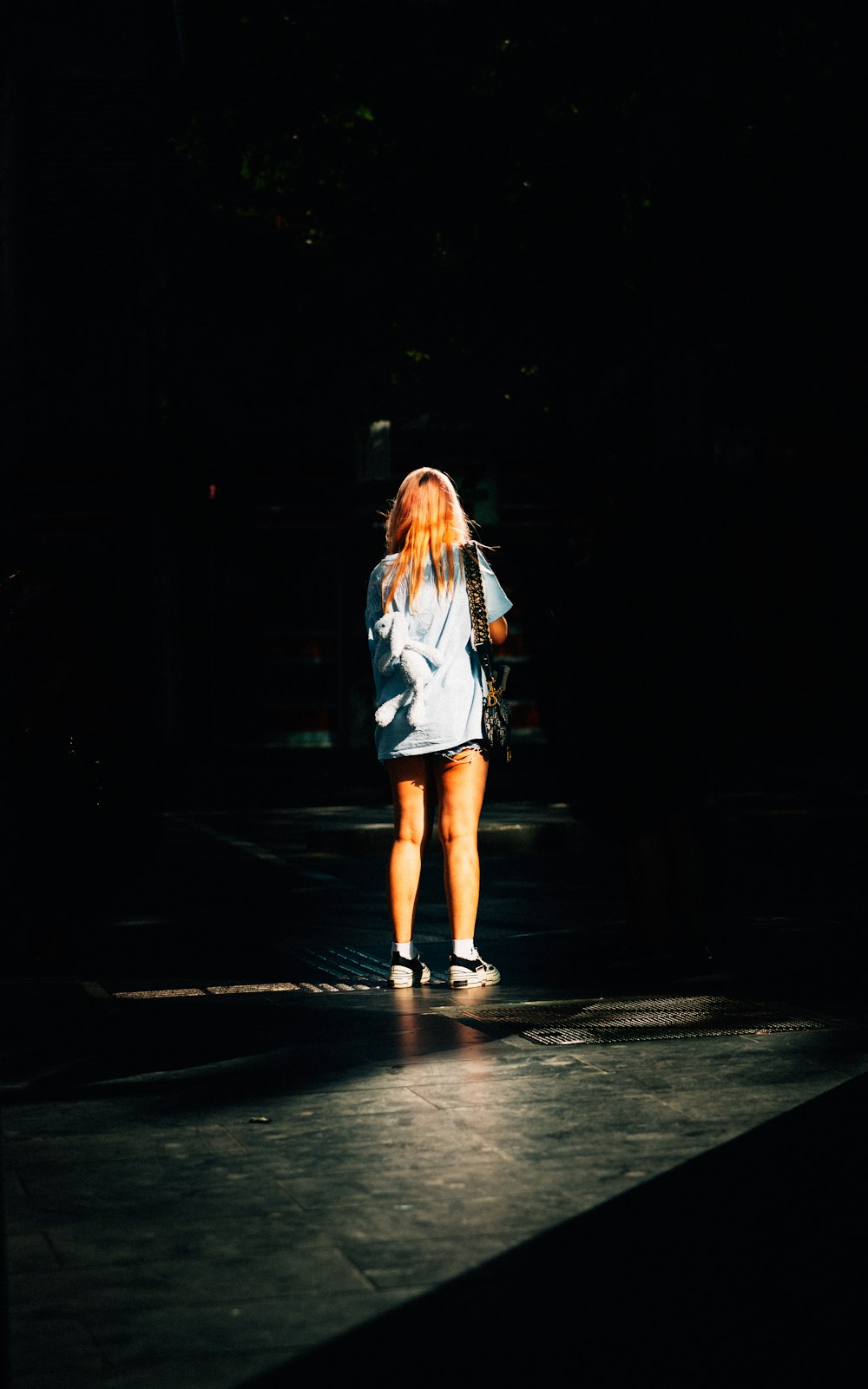 woman in white long sleeve shirt walking on black pathway