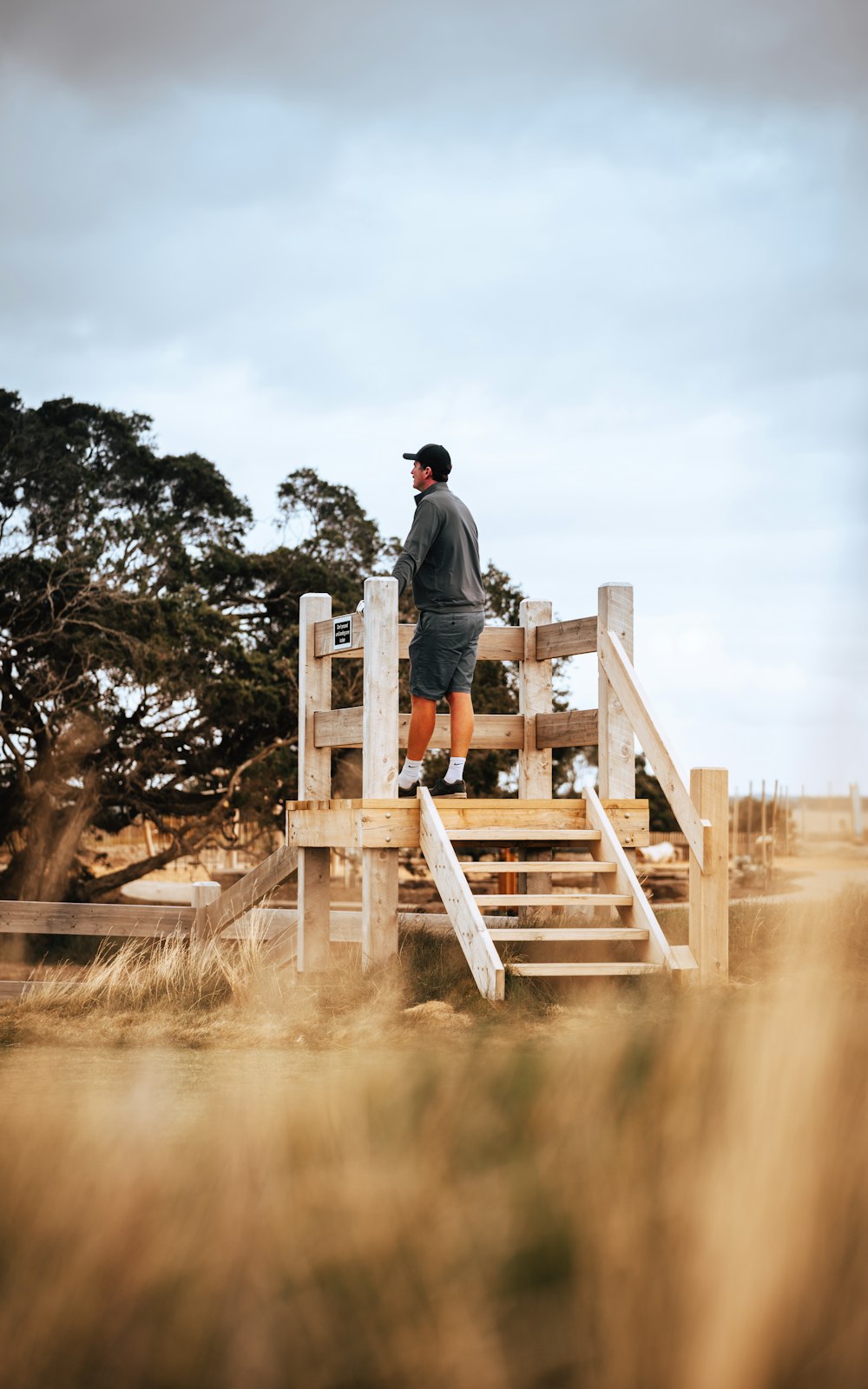 man in grey jacket and black pants standing on brown wooden dock during daytime