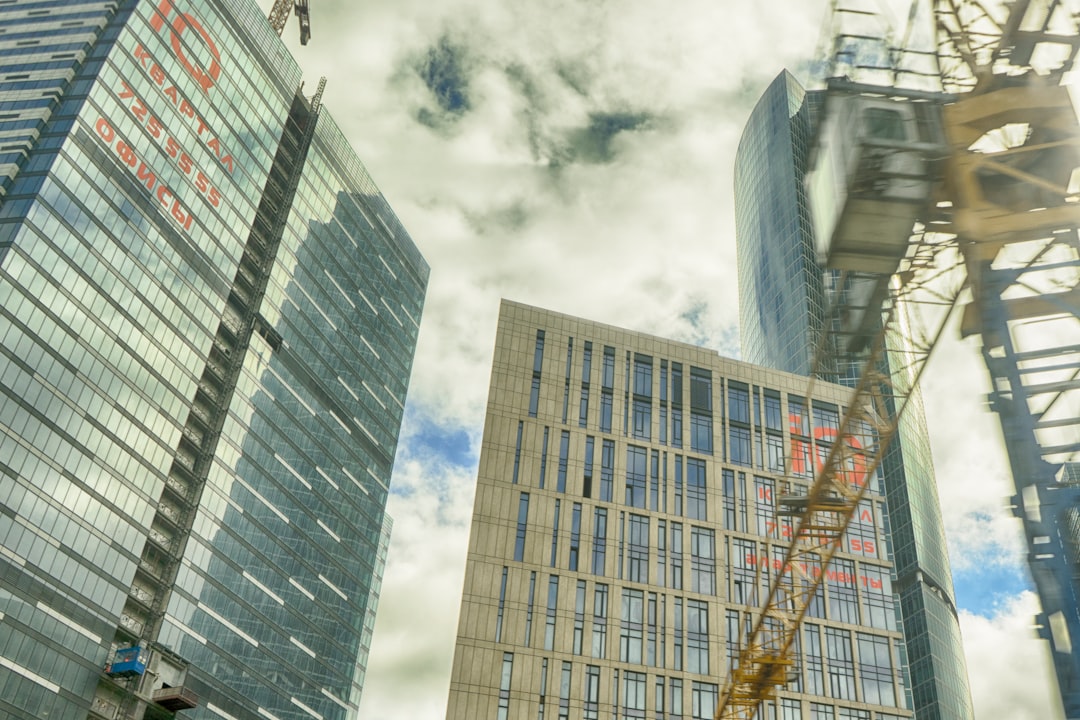 yellow crane near building under cloudy sky