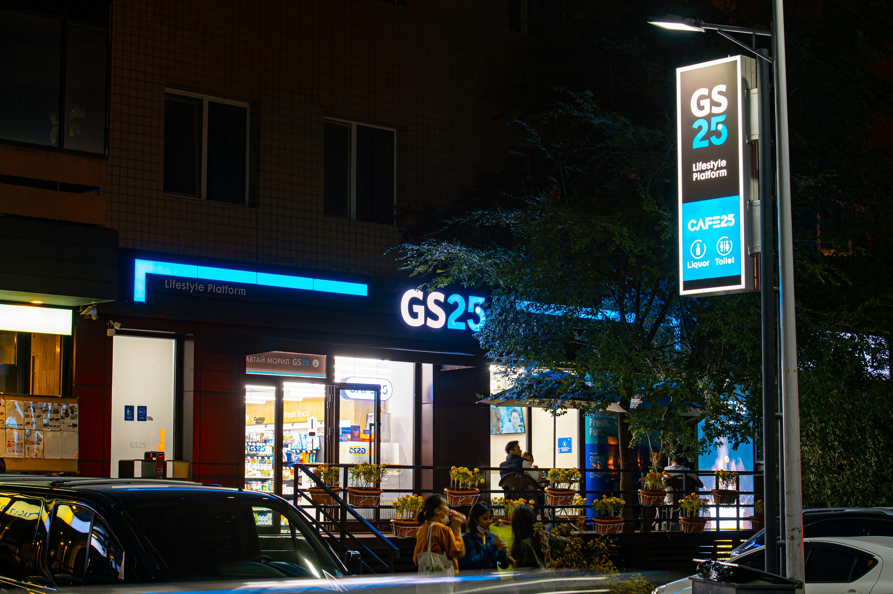 people walking on street near cars parked in front of store during night time