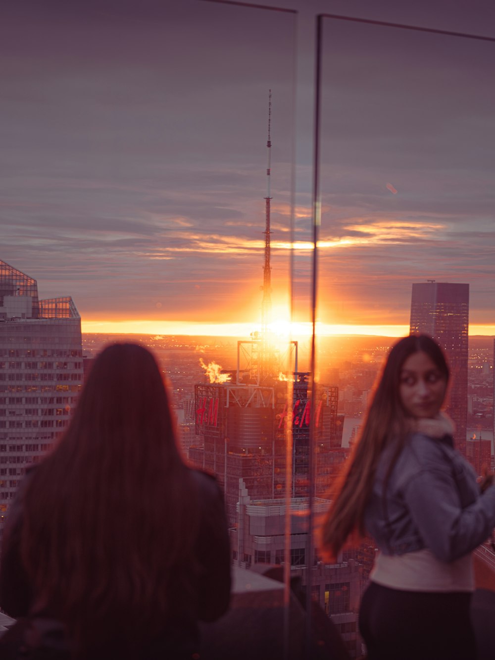 woman in gray jacket standing beside woman in white jacket during sunset