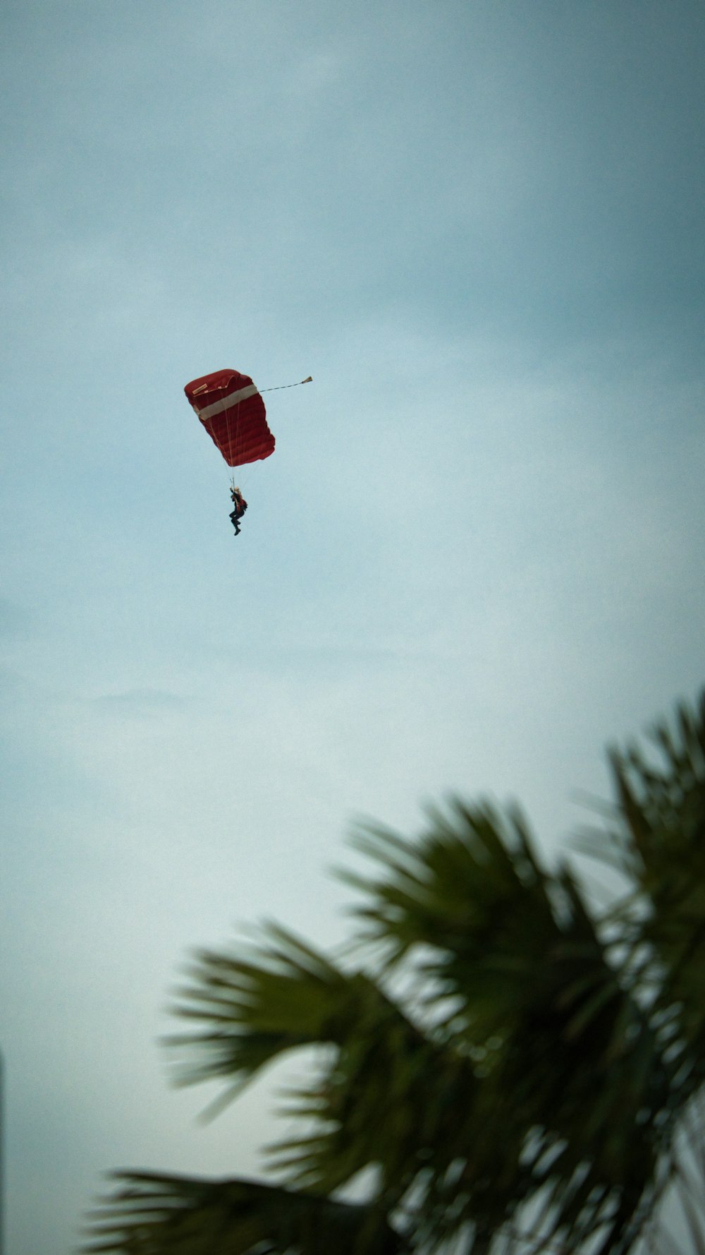 person in red parachute under white sky during daytime