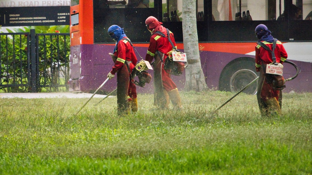 man in red jacket holding a stick near red bus during daytime