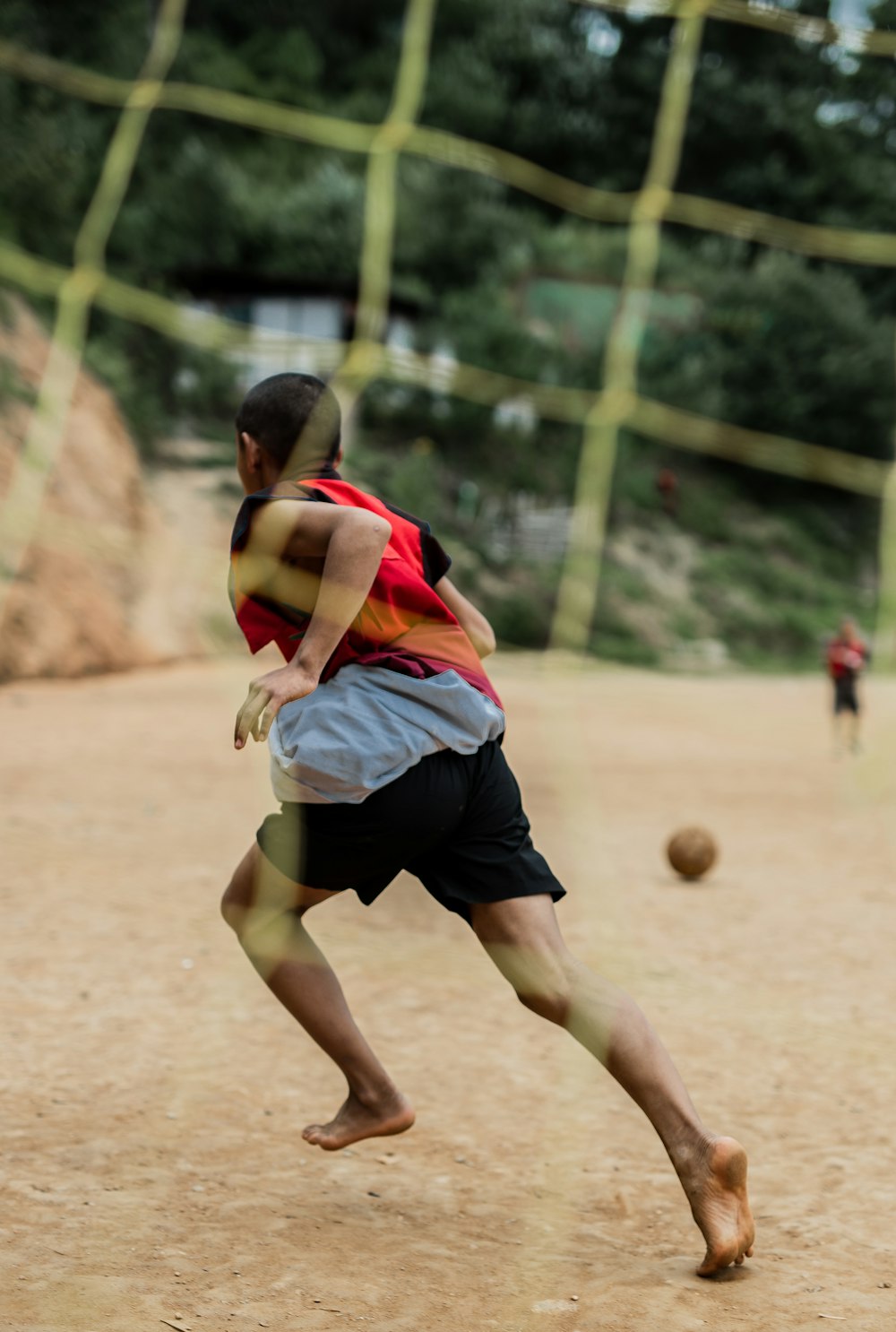 Niño con camisa de jersey azul y rojo jugando al fútbol durante el día