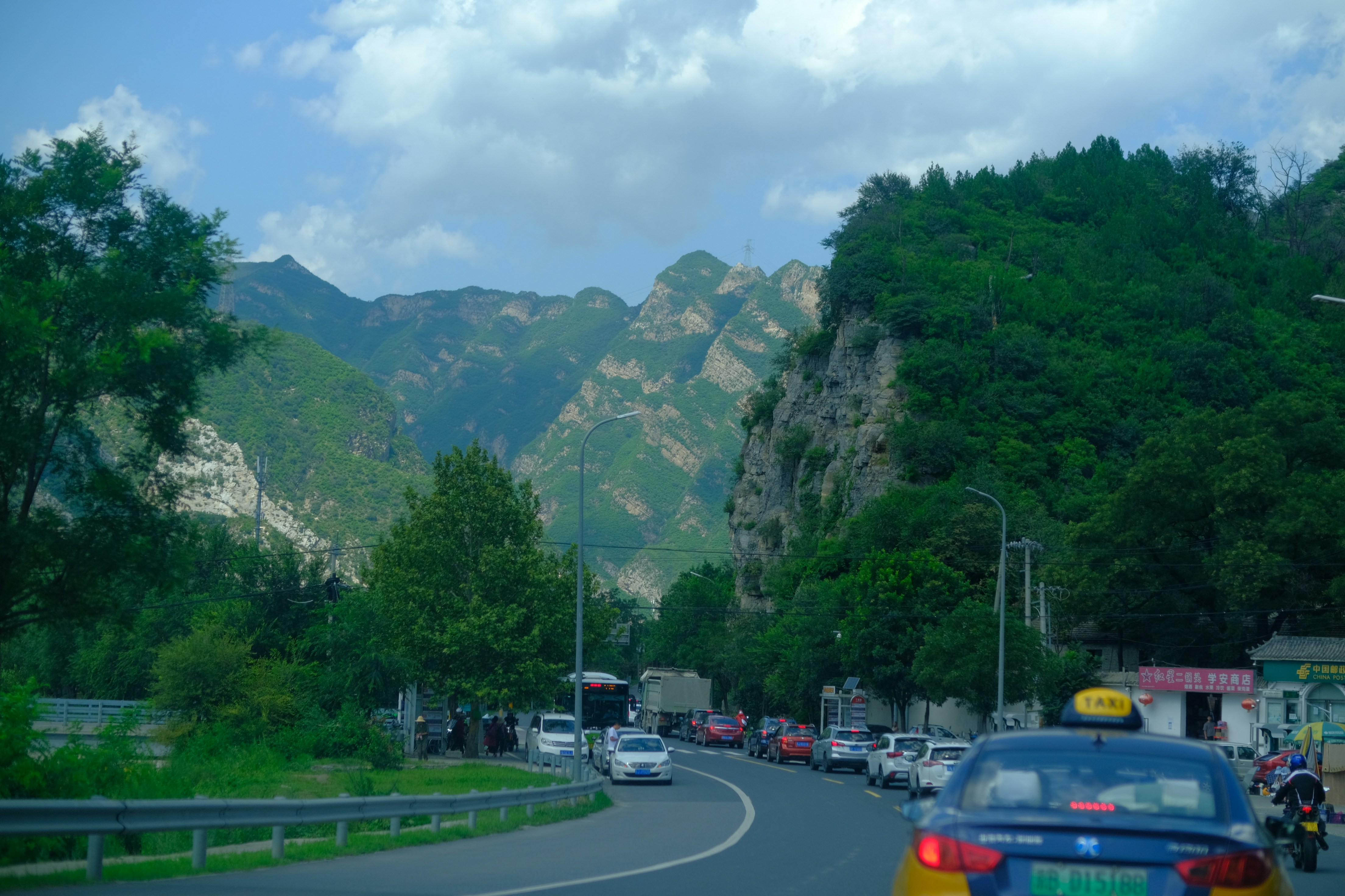 cars on road near green trees and mountain during daytime
