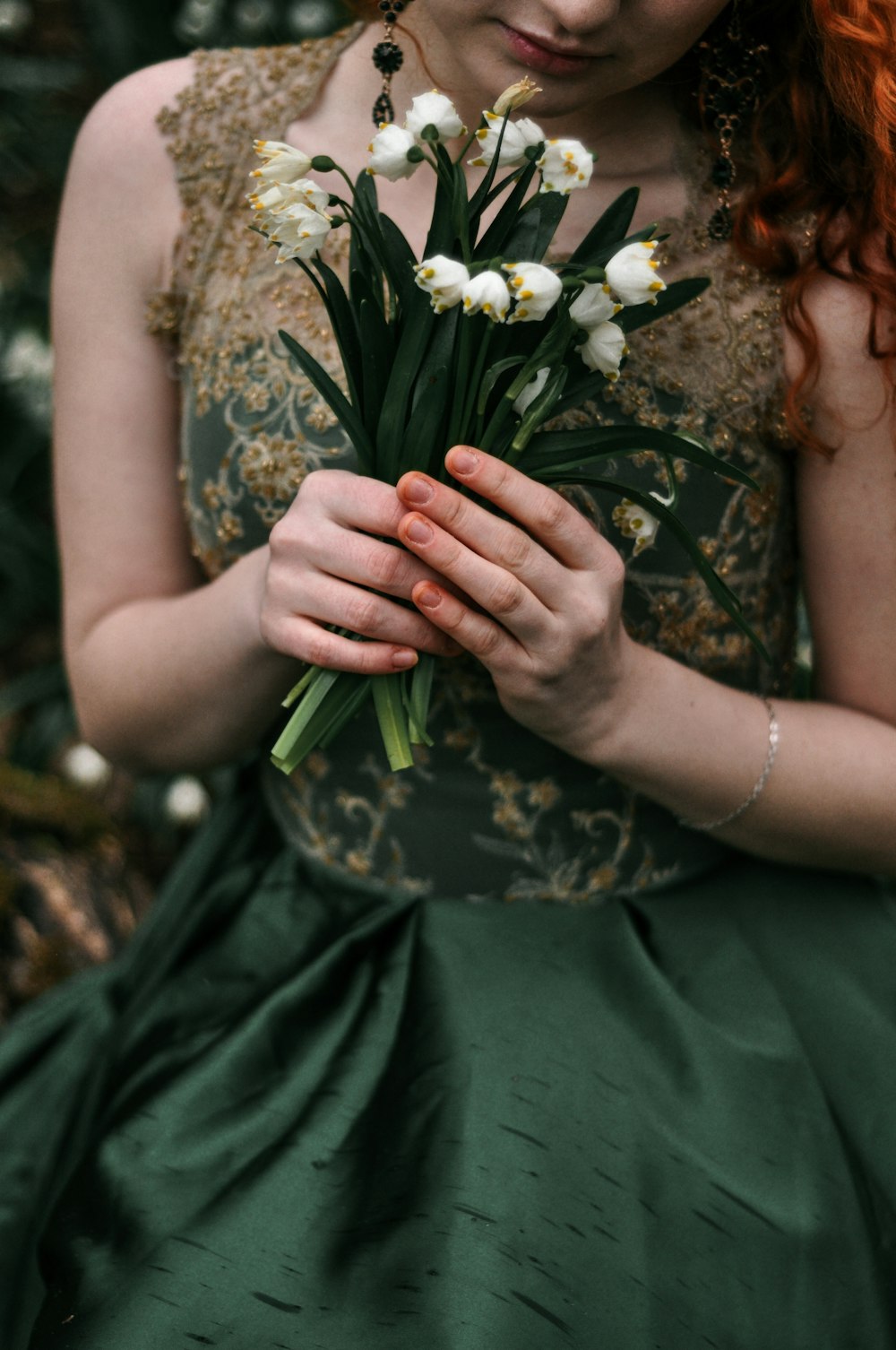 woman in green dress holding white flower bouquet