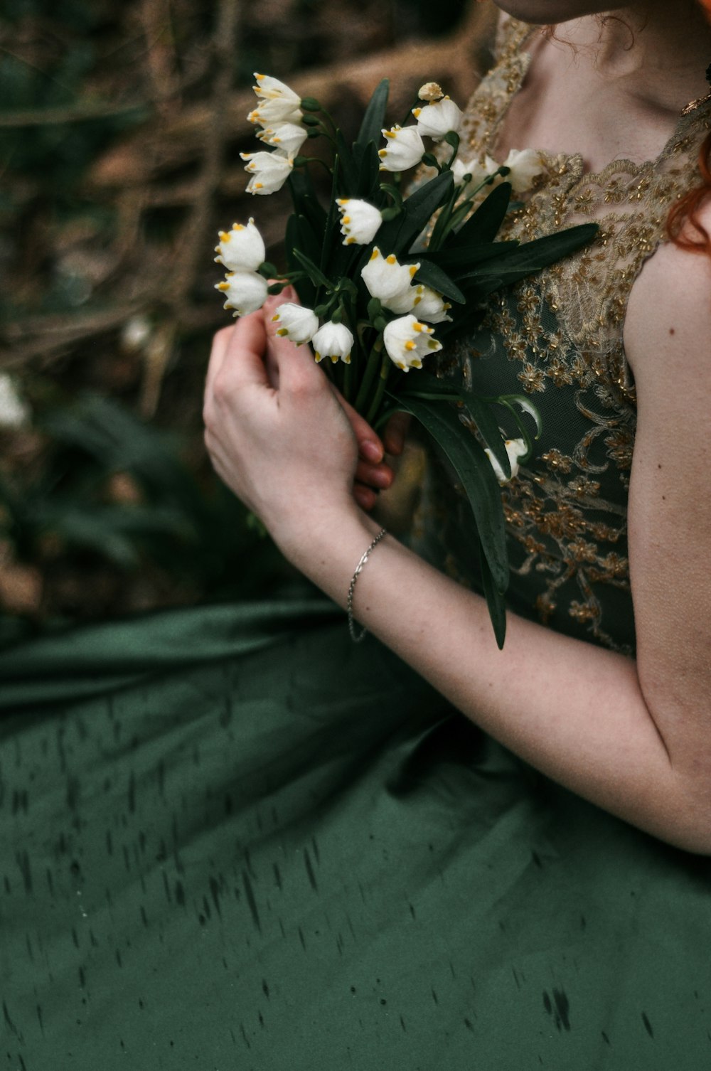 personne tenant des fleurs blanches et jaunes